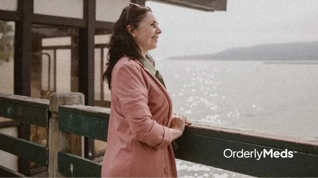 A middle aged woman going through menopause standing on a pier by the water