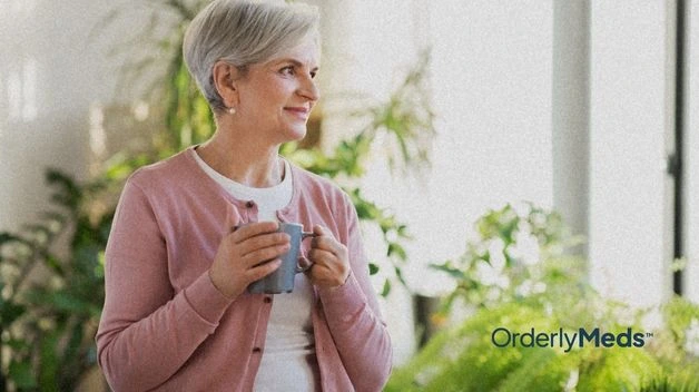 An older women on GLP-1 holding a blue mug of tea in front out indoor house plants