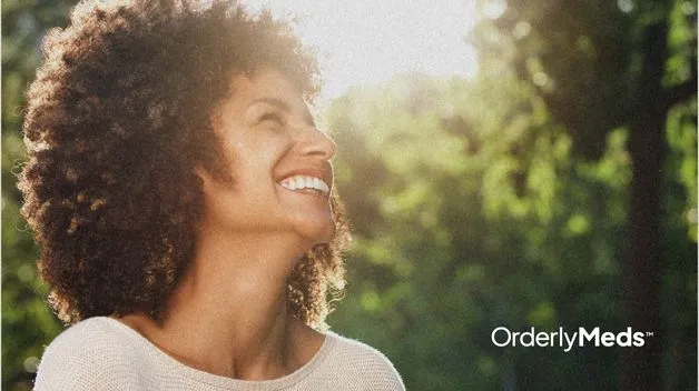 Close up of woman smiling outside on a sunny day after losing weight on GLP-1