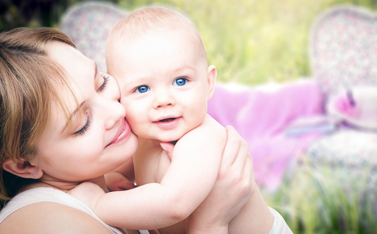 A woman smiling and holding a baby