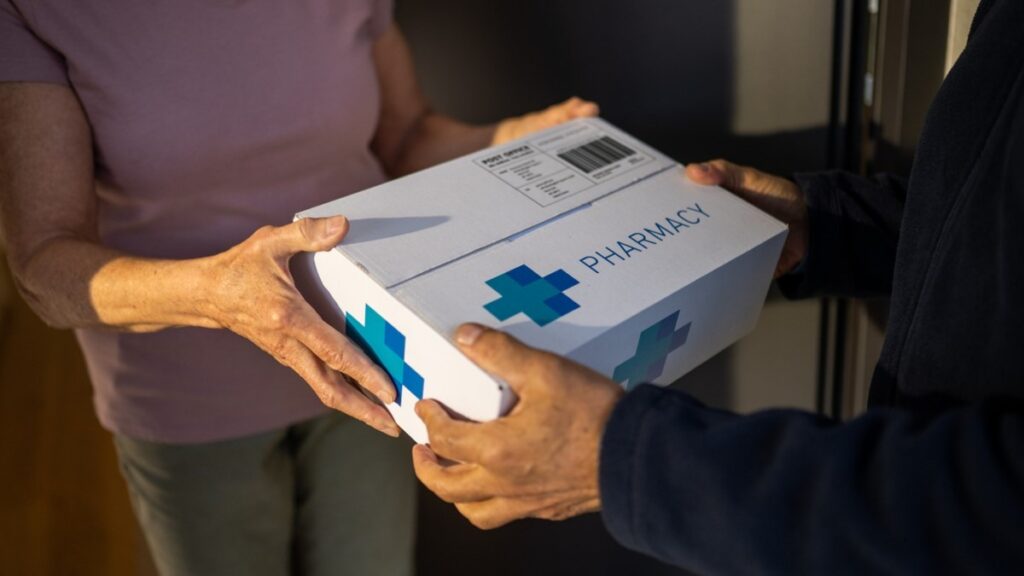 Courier handing a white pharmacy delivery box to a patient at their front door, illustrating home medication shipping after an online GLP-1 prescription.