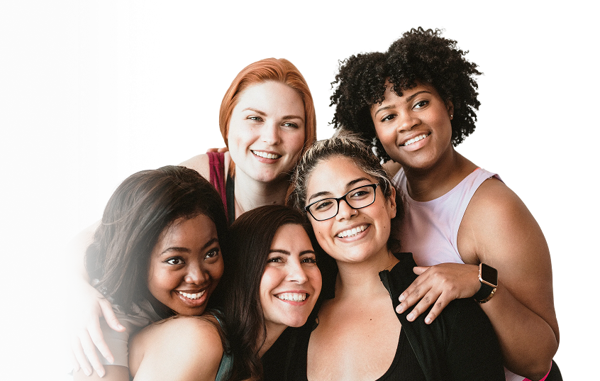 Group of five smiling, diverse women of varying backgrounds posing closely together in a warm, friendly embrace.